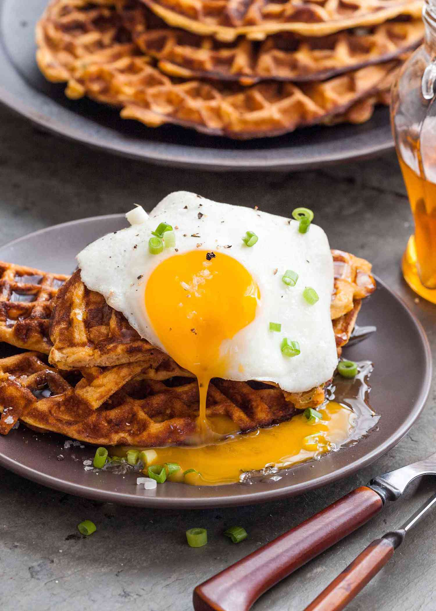 A plate of sweet potato waffles topped with a sunny side up egg and chives