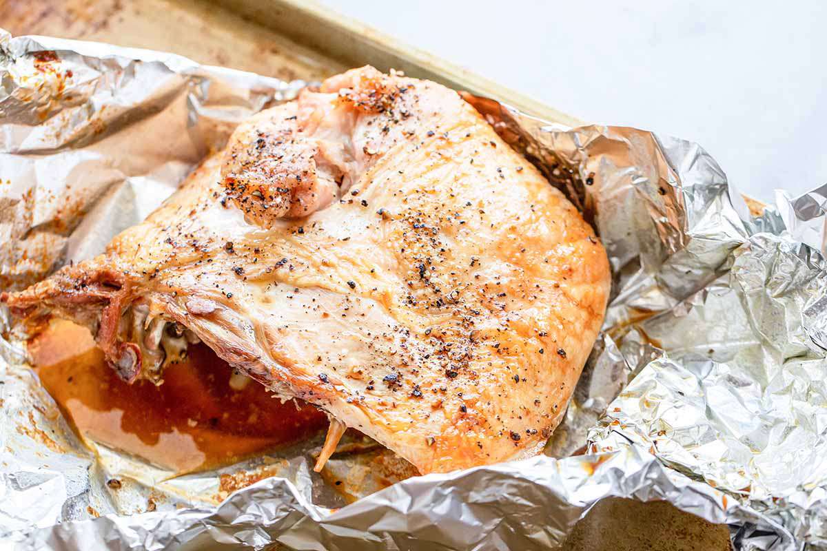 Juicy turkey on a baking sheet with foil underneath to make a homemade turkey club.