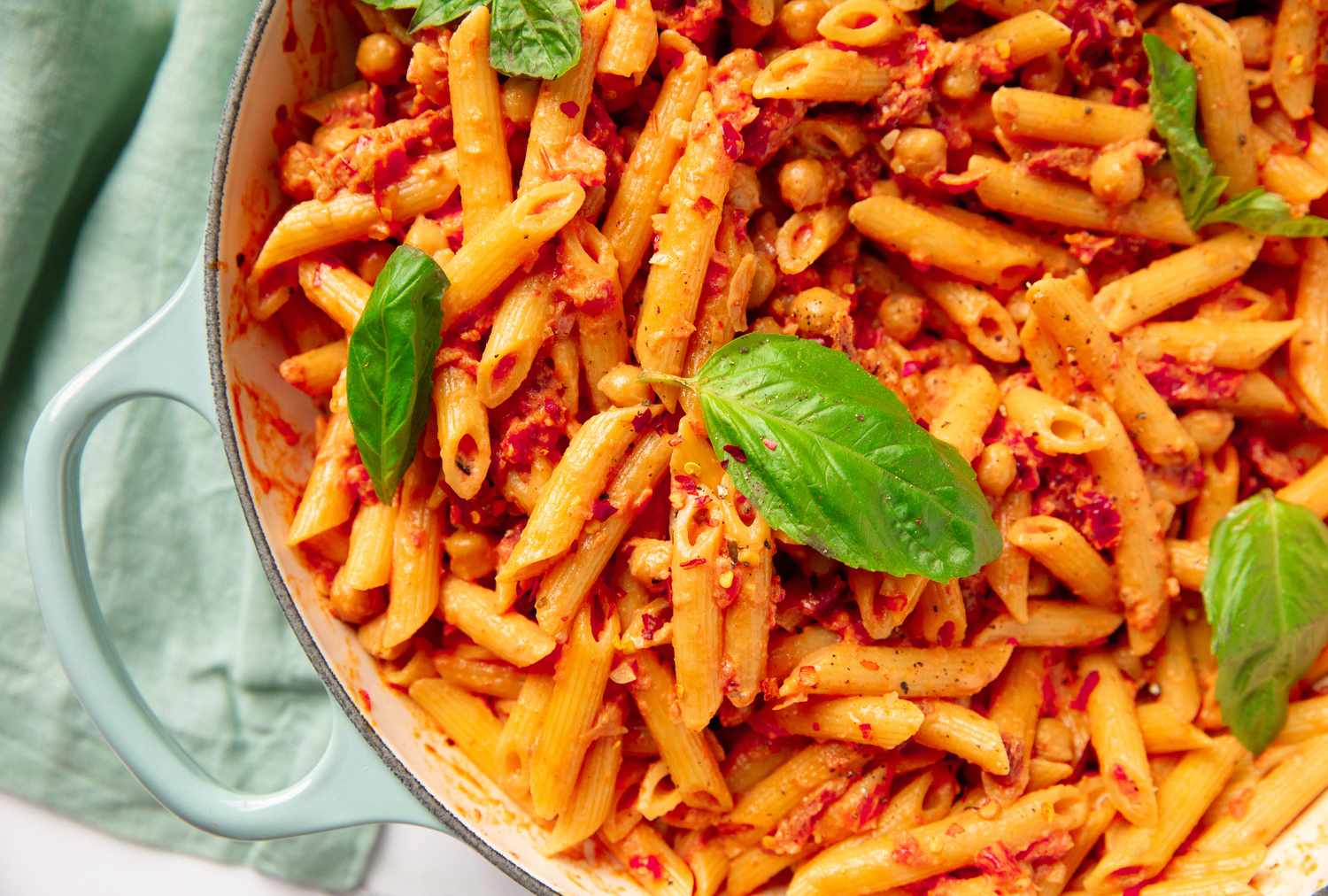 A close-up of cooked pasta with chickpeas and basil leaves