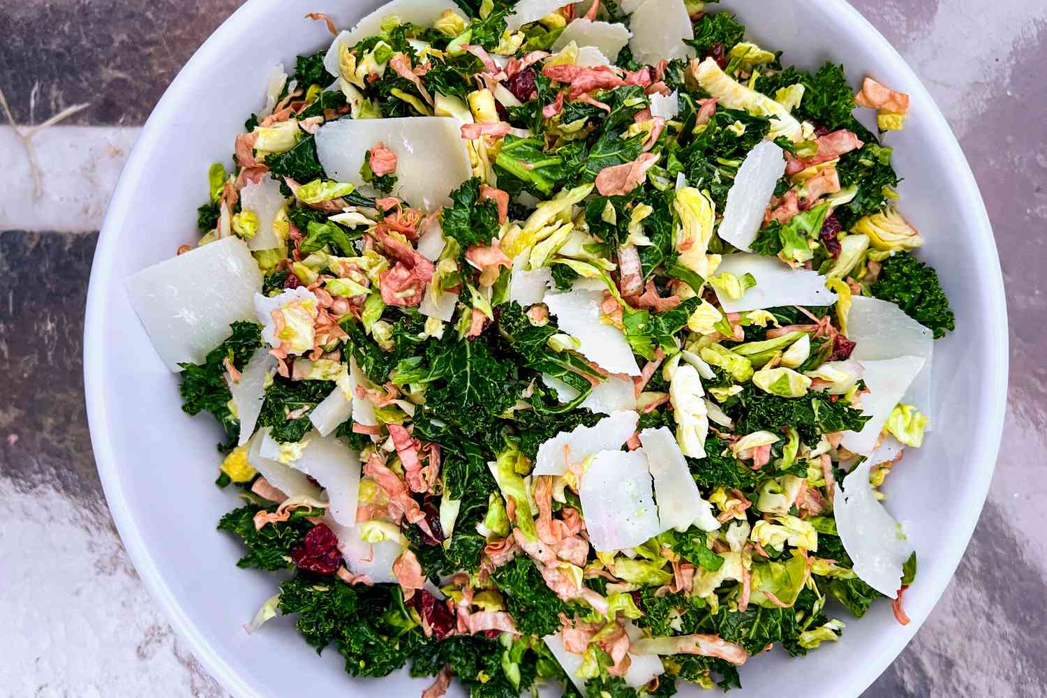 A vibrant, green salad of kale with Parmesan shavings on top