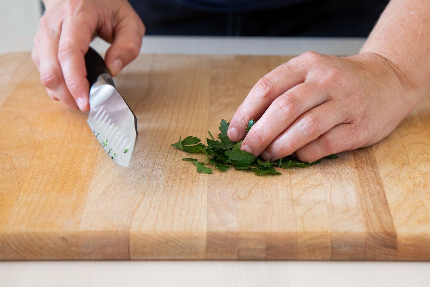Grabbing a knife to begin chopping a pile of parsley leaves