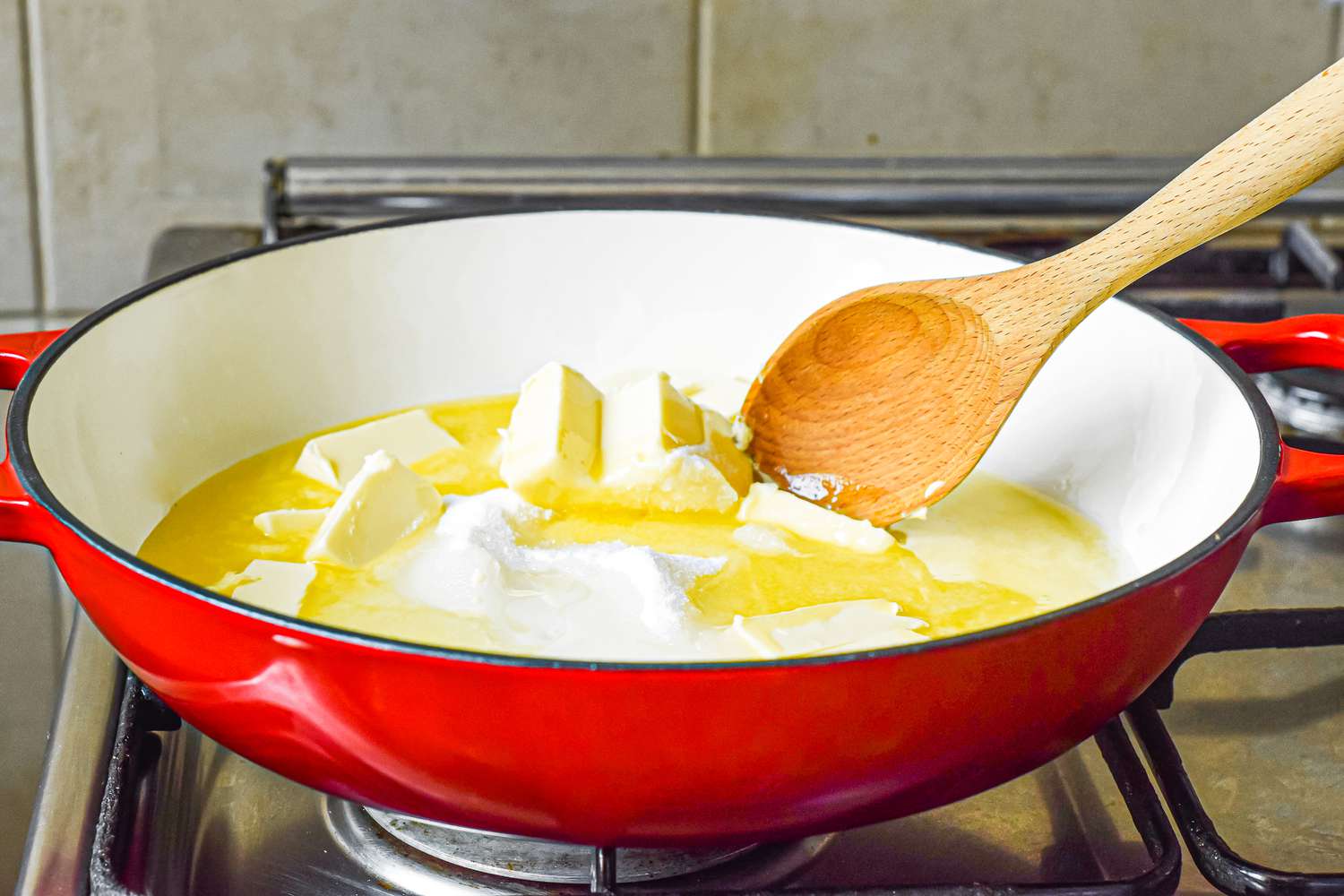 Melting butter in a red pan to make almond roca recipe.
