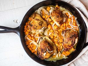 apple cider braised chicken thighs with sweet potatoes in black cast iron skillet