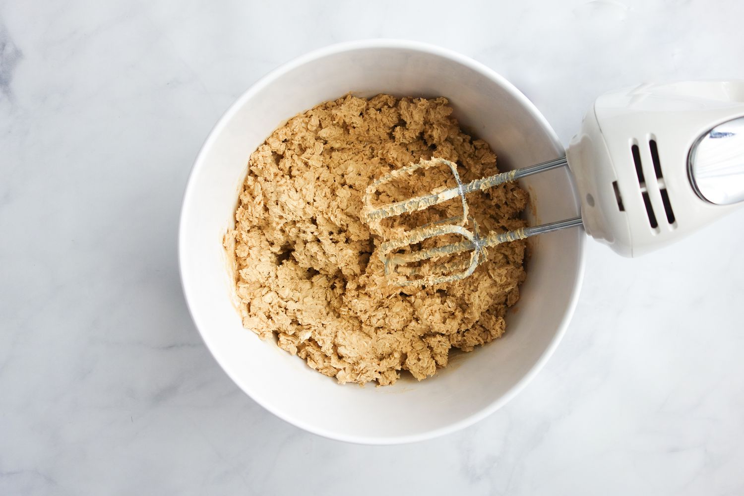 Chewy Peanut Butter Oatmeal Cookie Dough in a Bowl with an Handheld Mixer