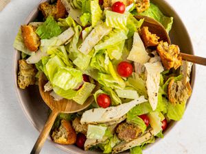 Two salad spoons used to mix sheet pan caesar salad