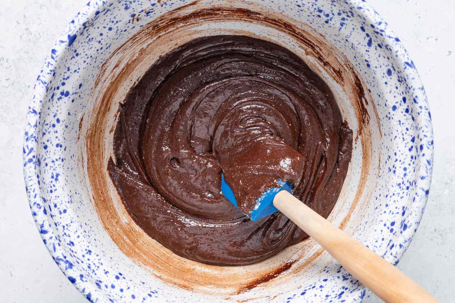 Homemade cosmic brownie mixture folded together using a rubber spatula 