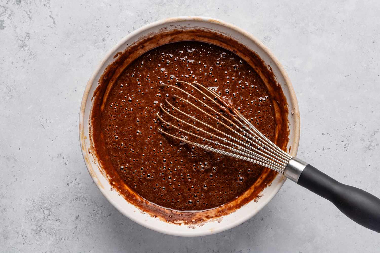 A whisk in a bowl with the bubbly and just whisked batter for the Chocolate stout loaf cake recipe