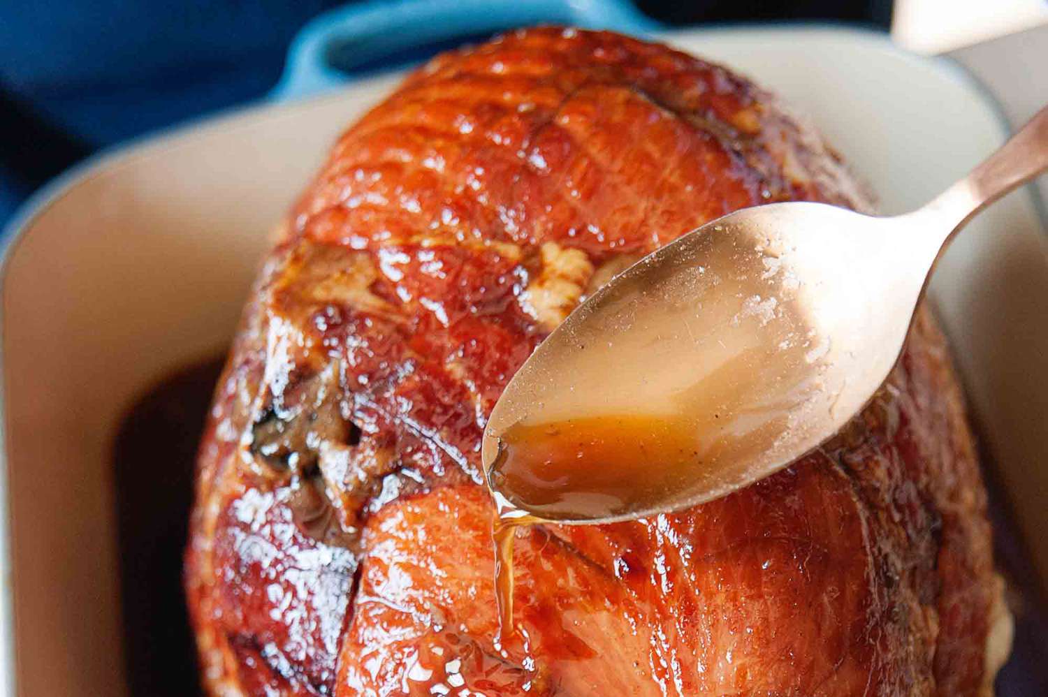 How to Cook a Ham Bone-In - spooning pan juices over whole ham