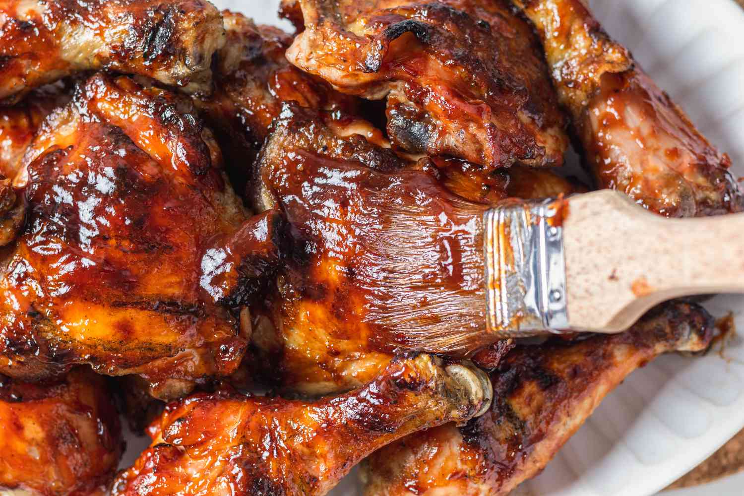 Brushing bbq sauce on barbecue chicken.