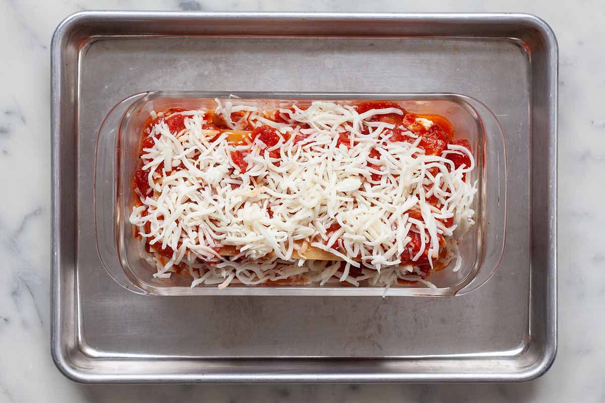 Unbaked loaf pan lasagna with sausage in a glass loaf pan sitting on top a baking sheet.