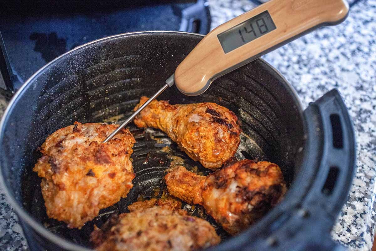 An instant-read thermometer inserted in an air fried chicken breast reading 148 degrees Fahrenheit 