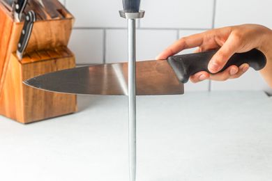 A hand honing a chef's knife with a honing steel