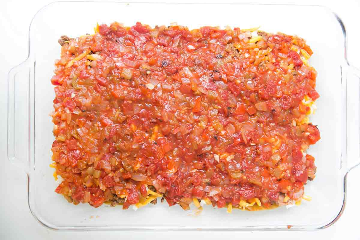 To make mexican lasagna, spread half the sauce over the beans, beef, and cheese