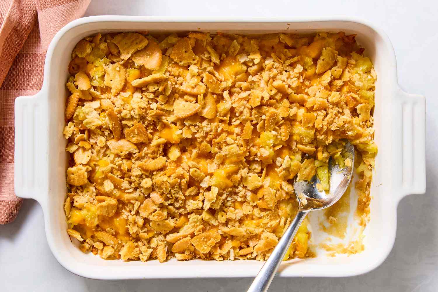 Pineapple Casserole in a casserole dish with a large serving spoon next to a scooped out section