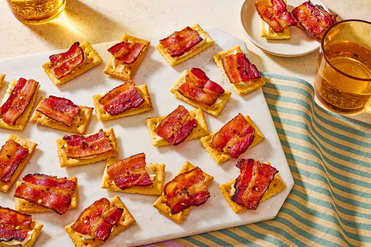 Overhead view of a serving board of millionaire crackers appetizer on top of a striped cloth napkin