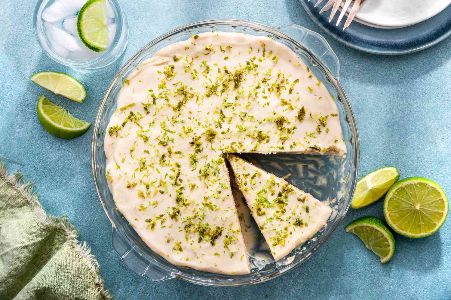 Lime icebox cake in a glass dish with one piece cut out and lime slices on the side