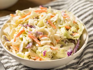 A bowl of coleslaw on striped napkin. 