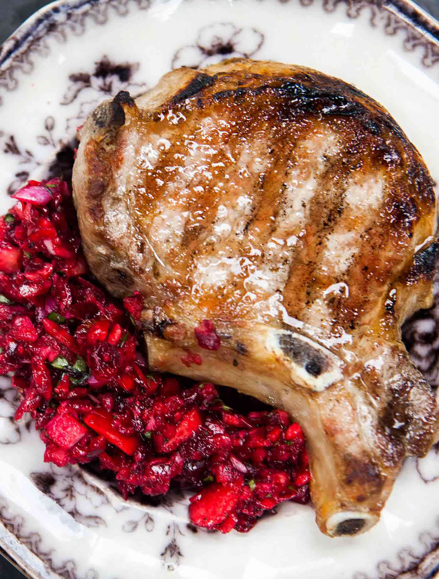 A plate of cherry salsa with a pork chop on top, ready to eat and serve