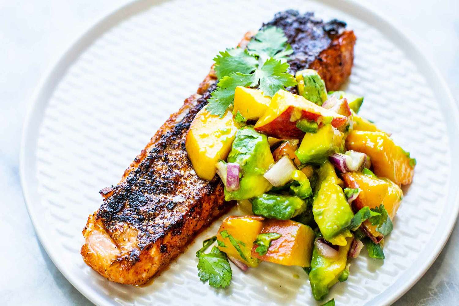 A plate of grilled salmon with peach salsa
