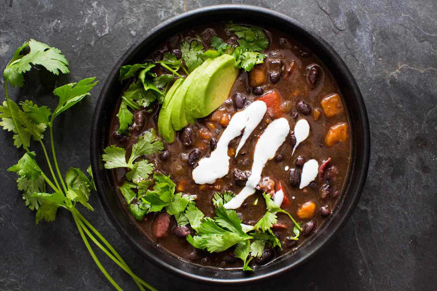 Black Bean Soup in a bowl garnished with avocado and cilantro 