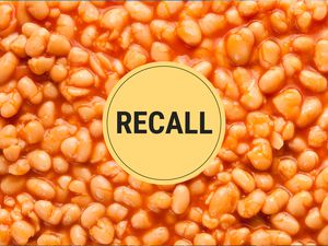 A zoomed in photo of baked beans with a recall sticker in the center. 