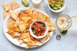 Plate of Homemade Tortilla Chips with a Bowl of Salsa, and Next to the Plate, a Bowl of Guacamole and Two Glasses of Beer