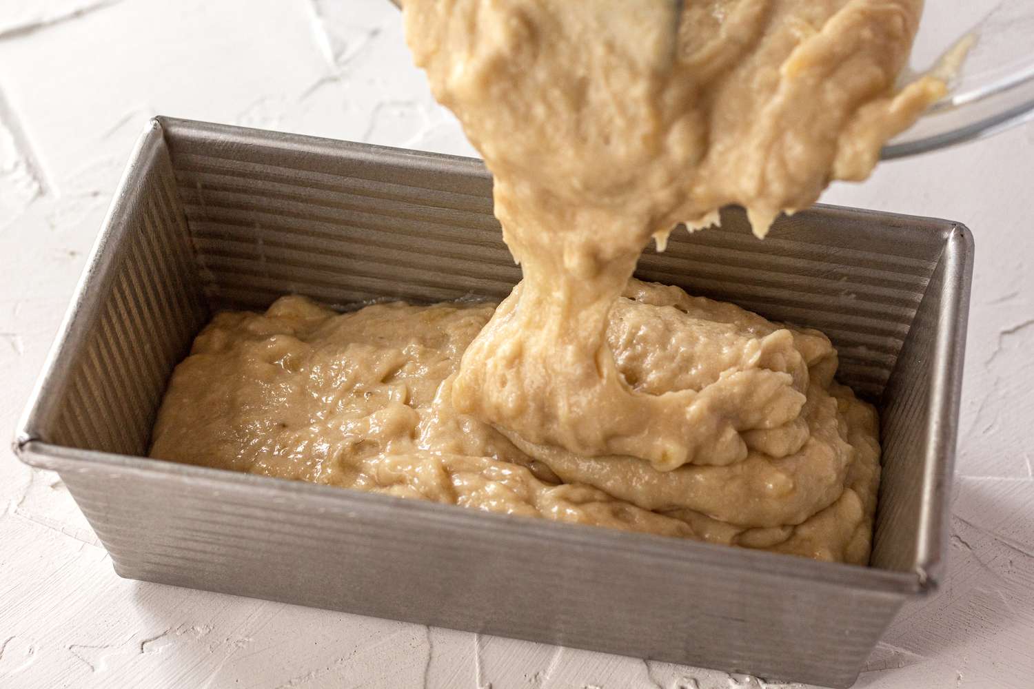 Banana bread batter poured into a loaf pan.