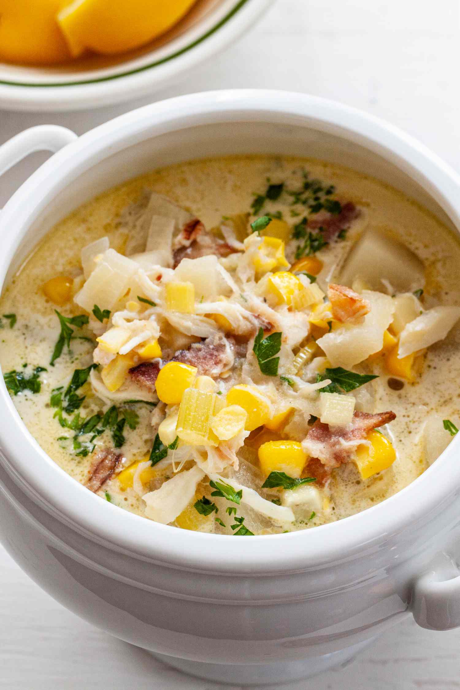 Corn and Crab Chowder in a Soup Bowl with Handles Next to a Bowl of Lemon Slices