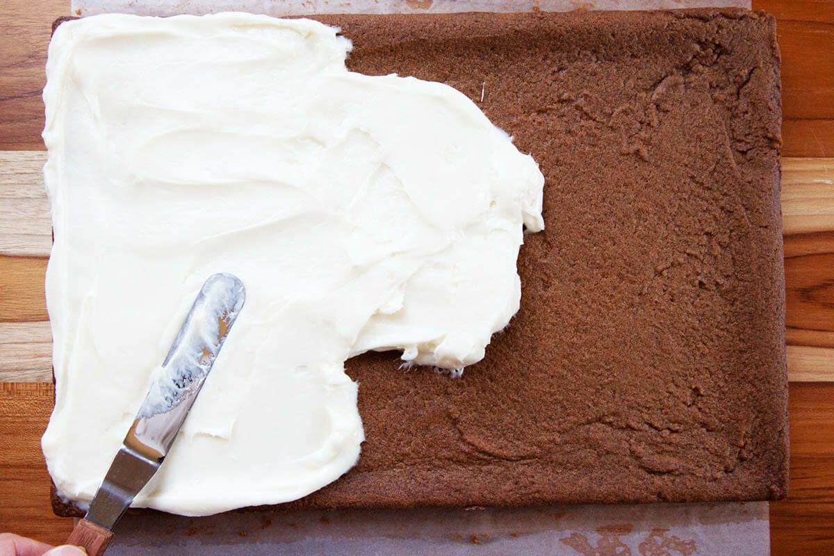 Best Gingerbread Bars being frosted with cream cheese frosting.