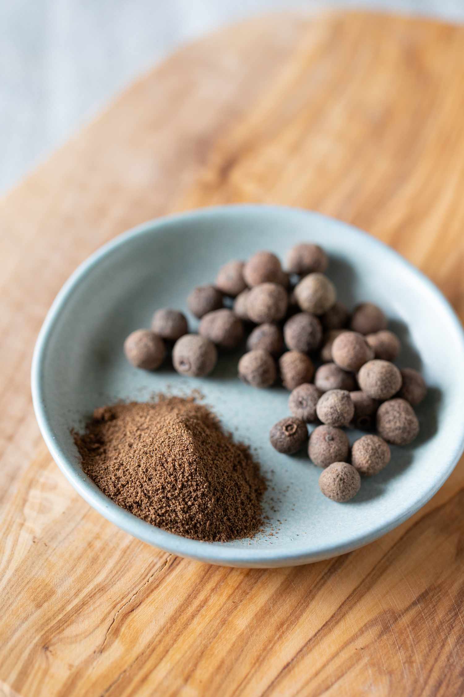 whole and ground allspice on wooden cutting board