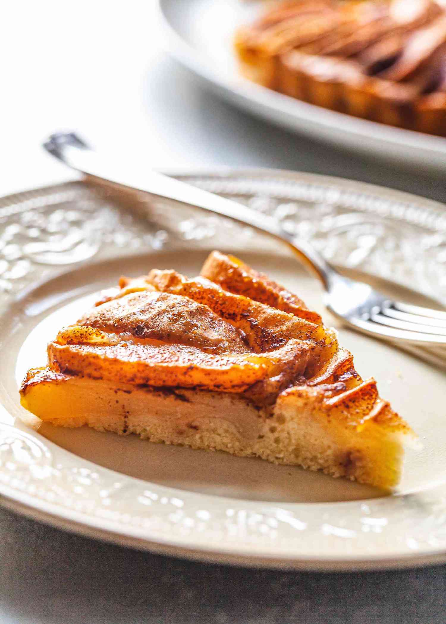 Slice of homemade pear cake on a plate with a fork.