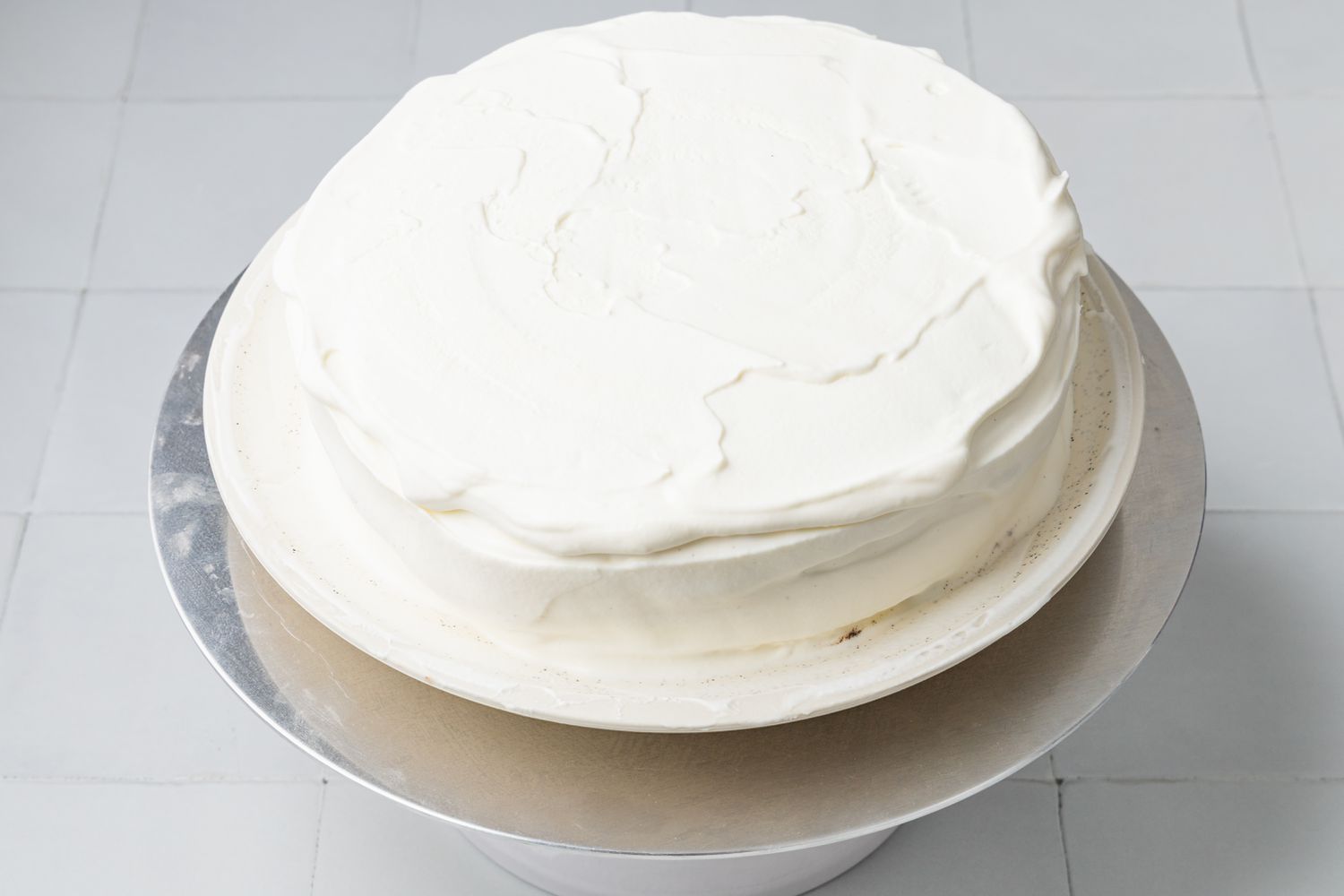Ice Cream Cake Covered With Whipped Cream. Ice Cream Cake Is Still on the Plate and the Plate Is on a Cake Stand