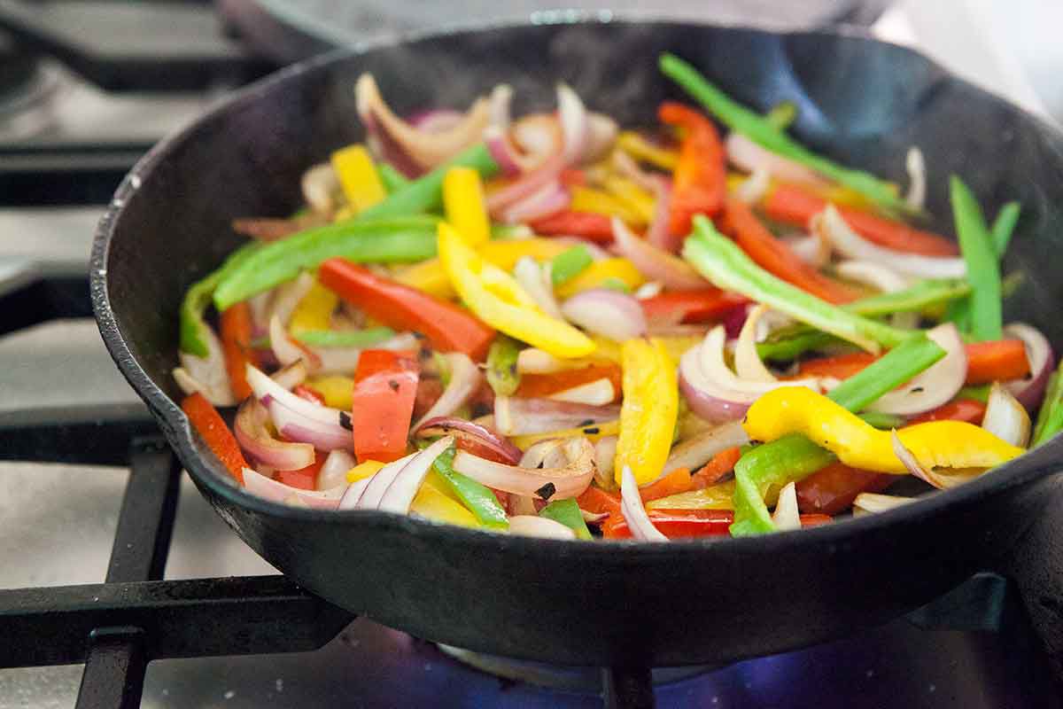 Bell peppers and onions cooking on a cast iron skillet