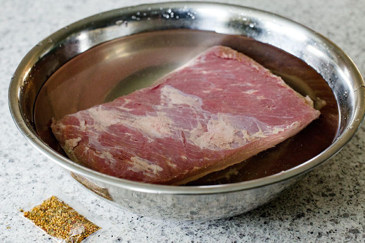 Instant Pot Corned Beef - corned beef in water in a bowl