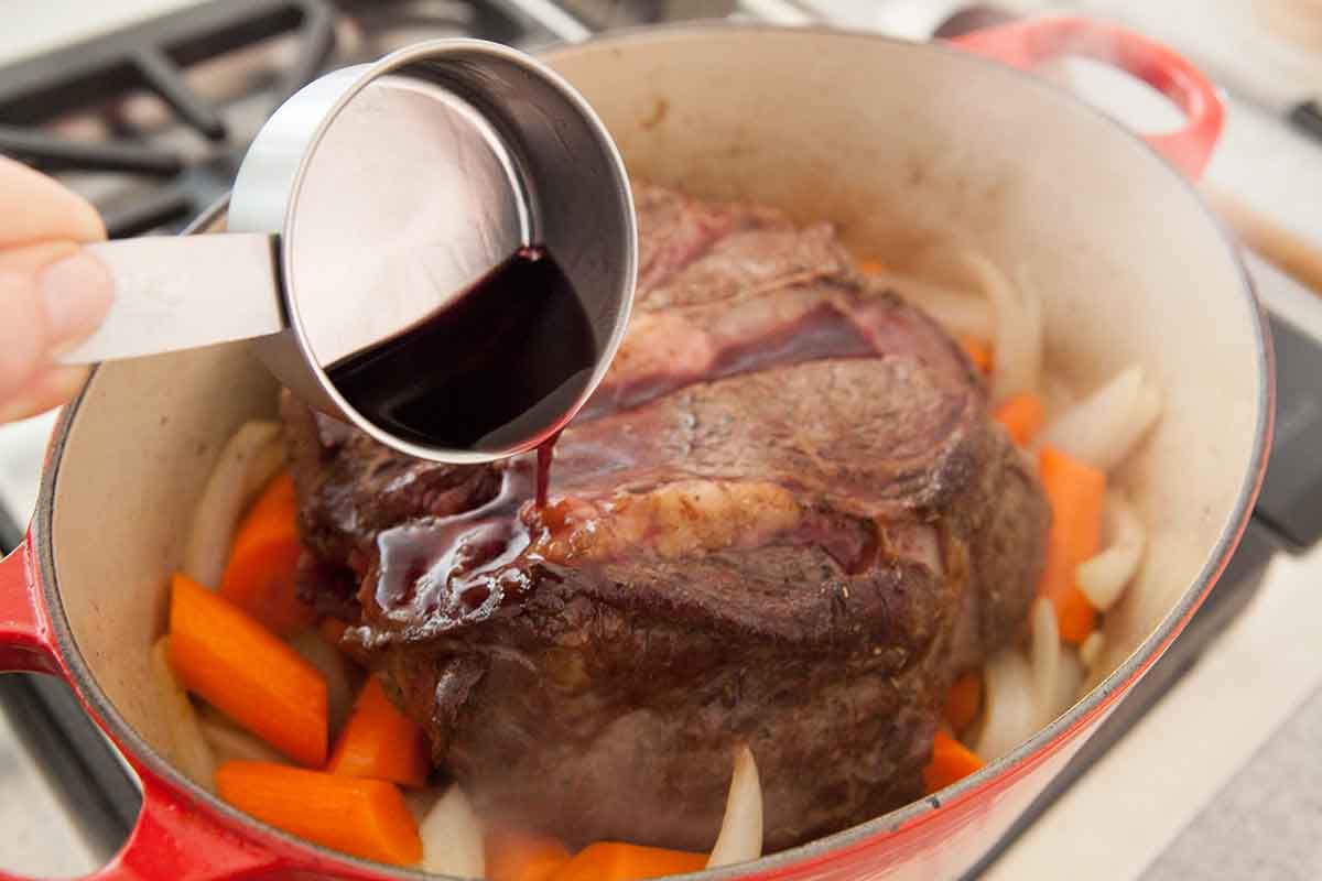 Flavoring Meat for Pot Roast in a Dutch oven with carrots and onions