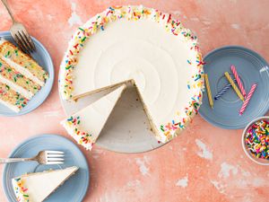 Confetti Cake Surrounded by Cake Slices on Small Plates and a Bowl of Sprinkles