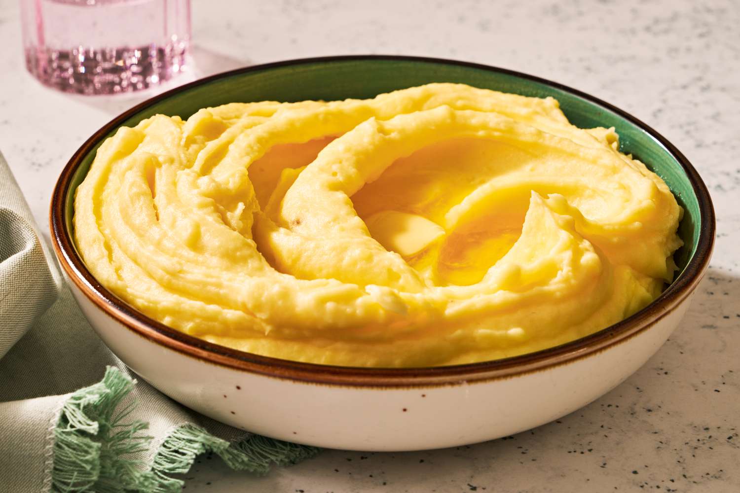 A bowl of mashed potatoes with butter melting in the center