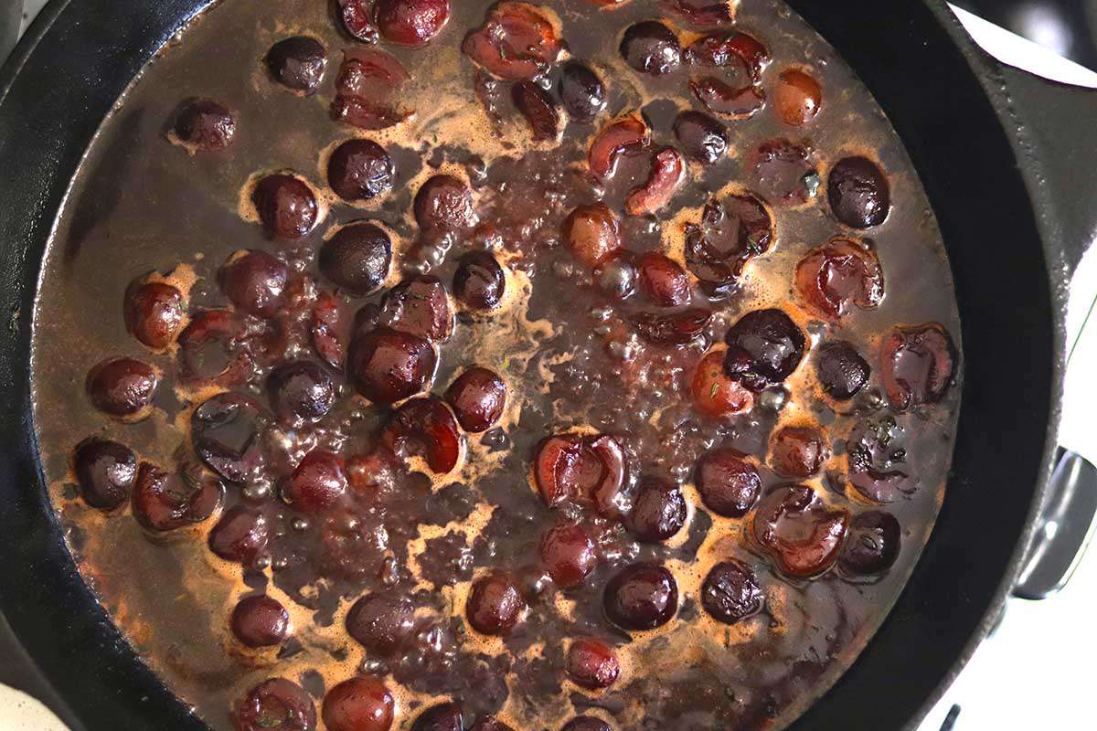 Cherries bubbling in a cast iron skillet for pan fried pork chops.
