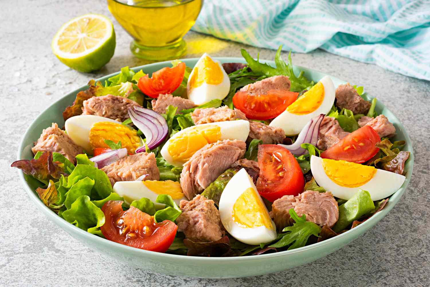 bowl of salad topped with tuna, egg wedges, and tomato wedges