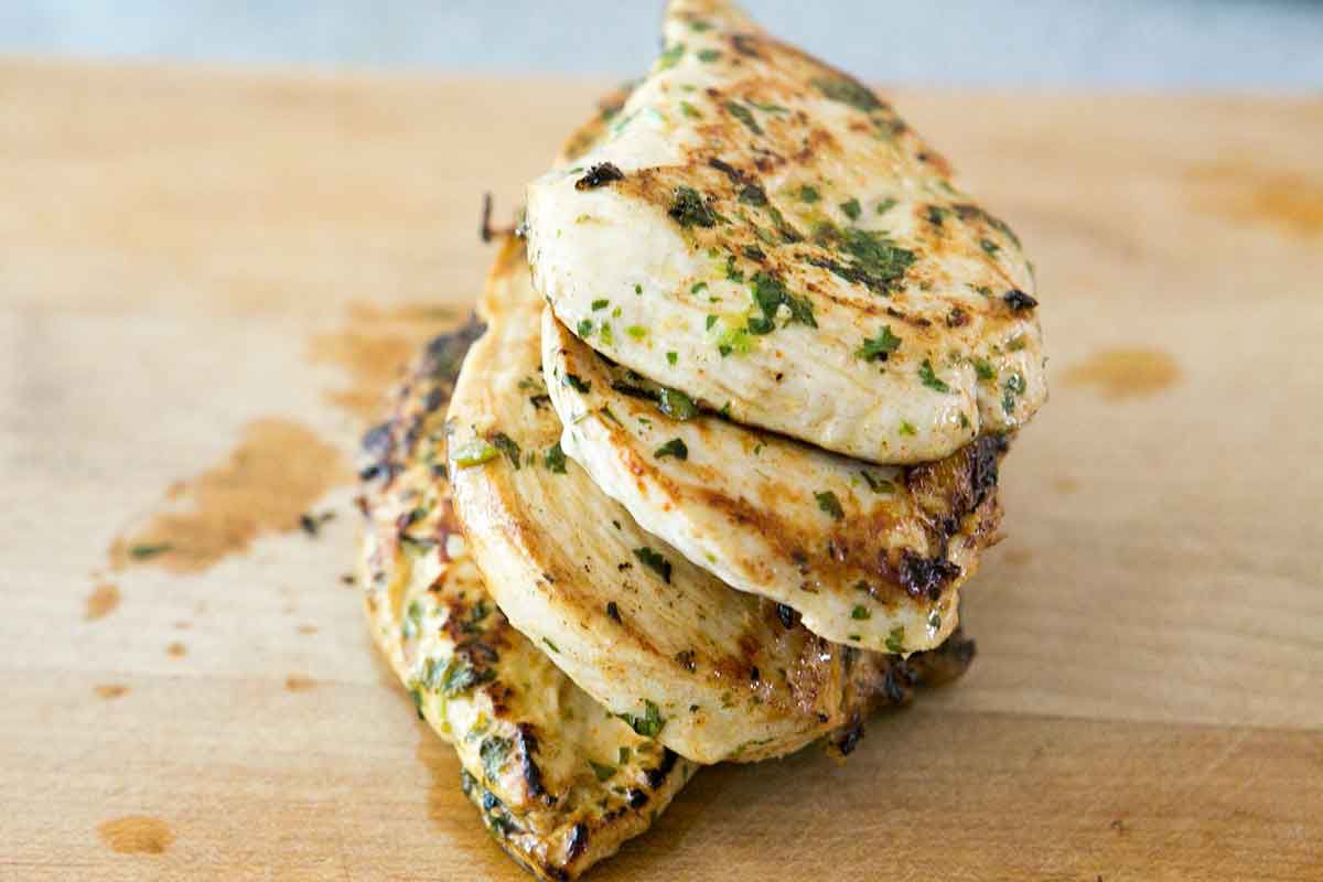 Cooked chicken in a stack resting on a cutting board