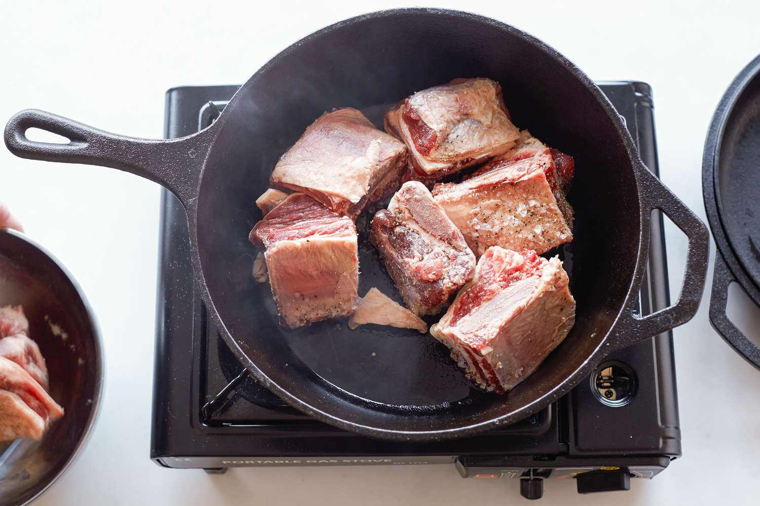 Short ribs searing in a cast iron skillet to make shortcut Korean braised short ribs 