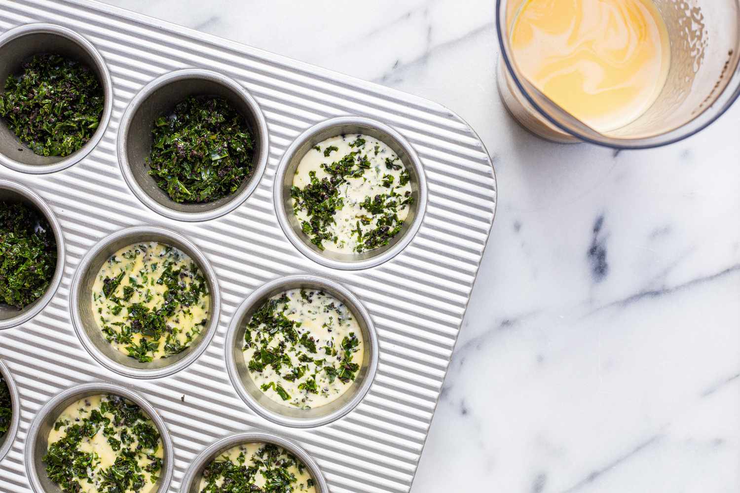 Cooked Kale and Portobello Added to Tins and Topped with Egg Mixture