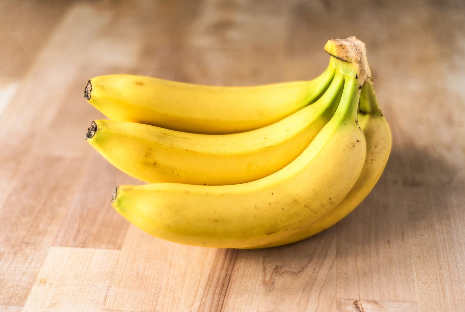 a bunch of ripe bananas on a wooden kitchen board