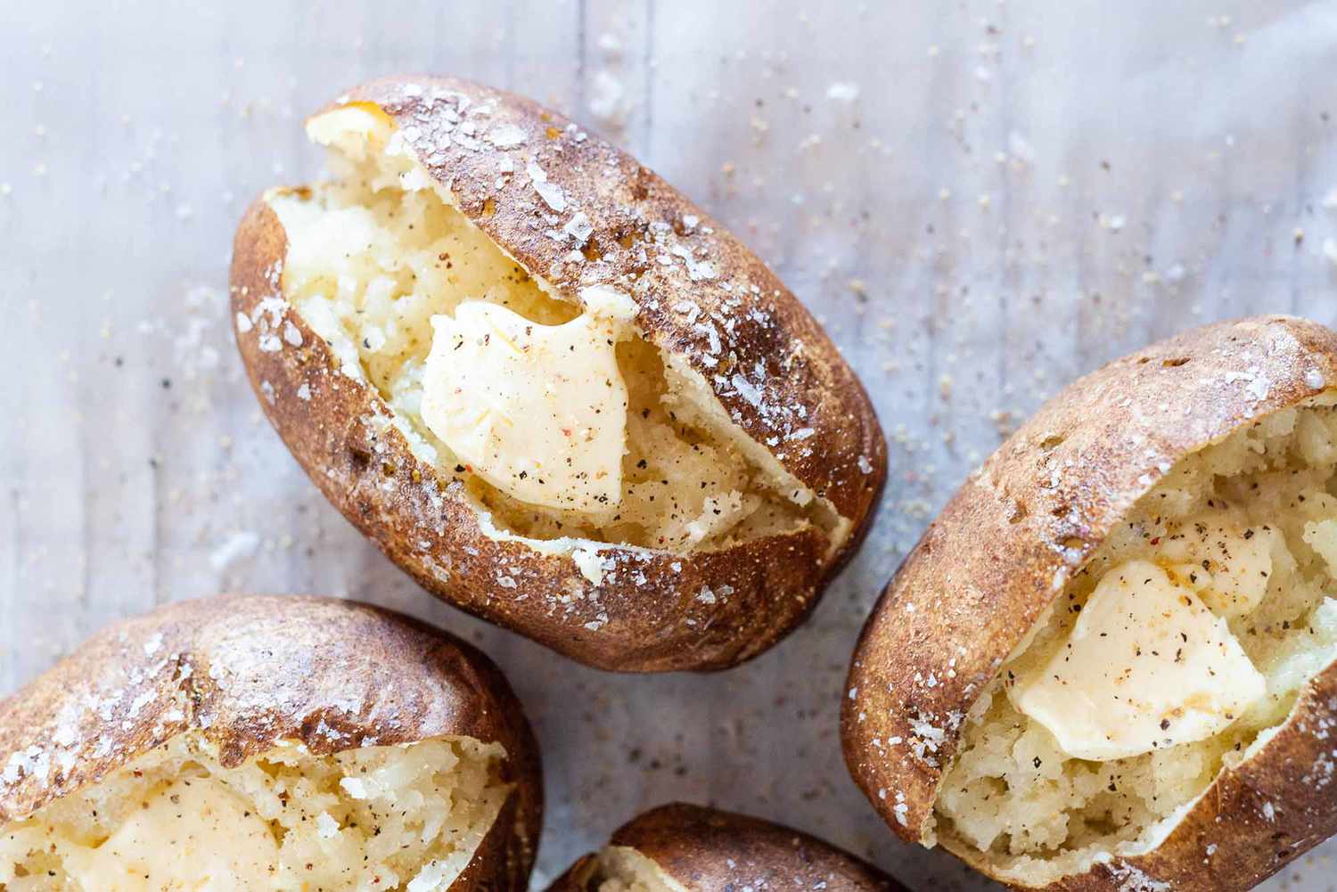 How to Bake a Potato -- 3 potatoes split open with butter