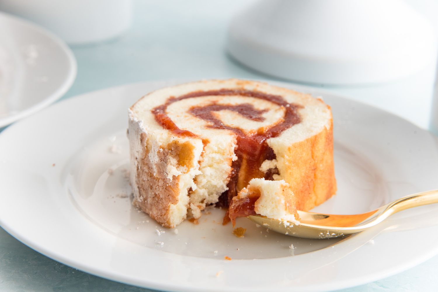 Side view of a piece of Guava Swiss Roll on a plate.