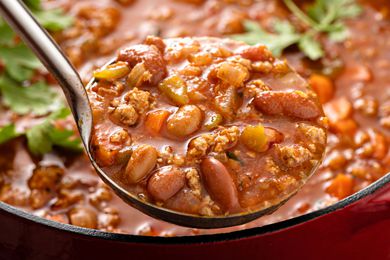 ladle of chili hovering over a pot of chili