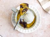 Mug of Banana Bread Chocolate Chunk Mug Cake Topped with a Dollop of Ice Cream and Spoonful of Cake Resting on Top of the Mug