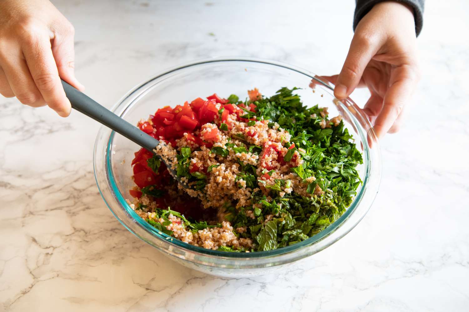 Mixing ingredients together for a tabbouleh recipe.