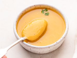 Spooning butternut squash soup out of a bowl.