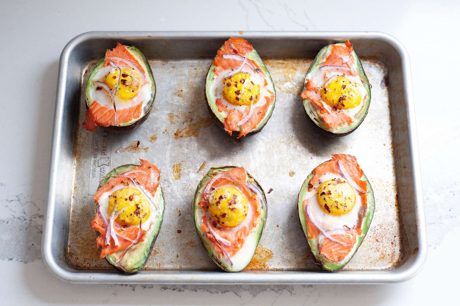 Baked eggs in avocado with everything bagel seasoning on a sheet pan.